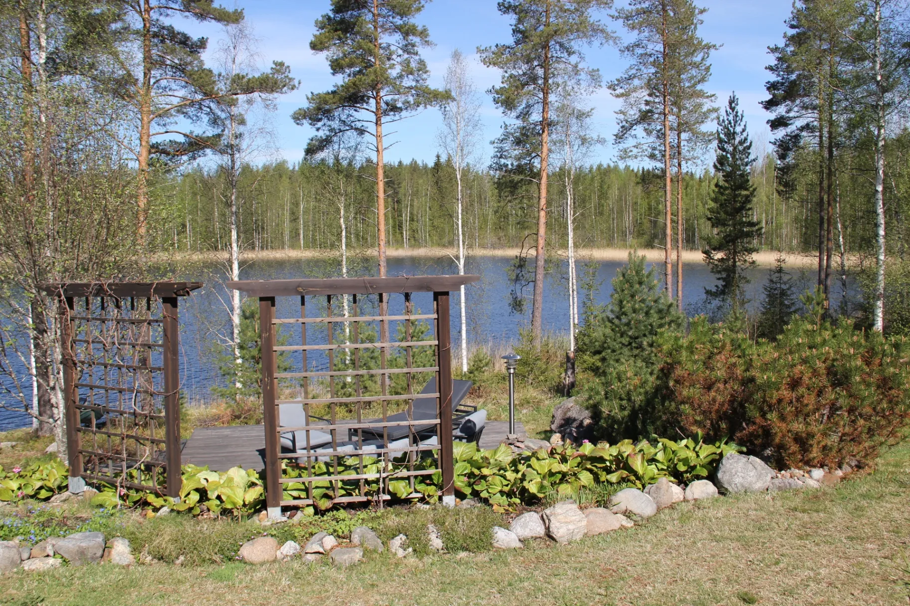 Trellised lakeside lounge area with the lake and forest beyond