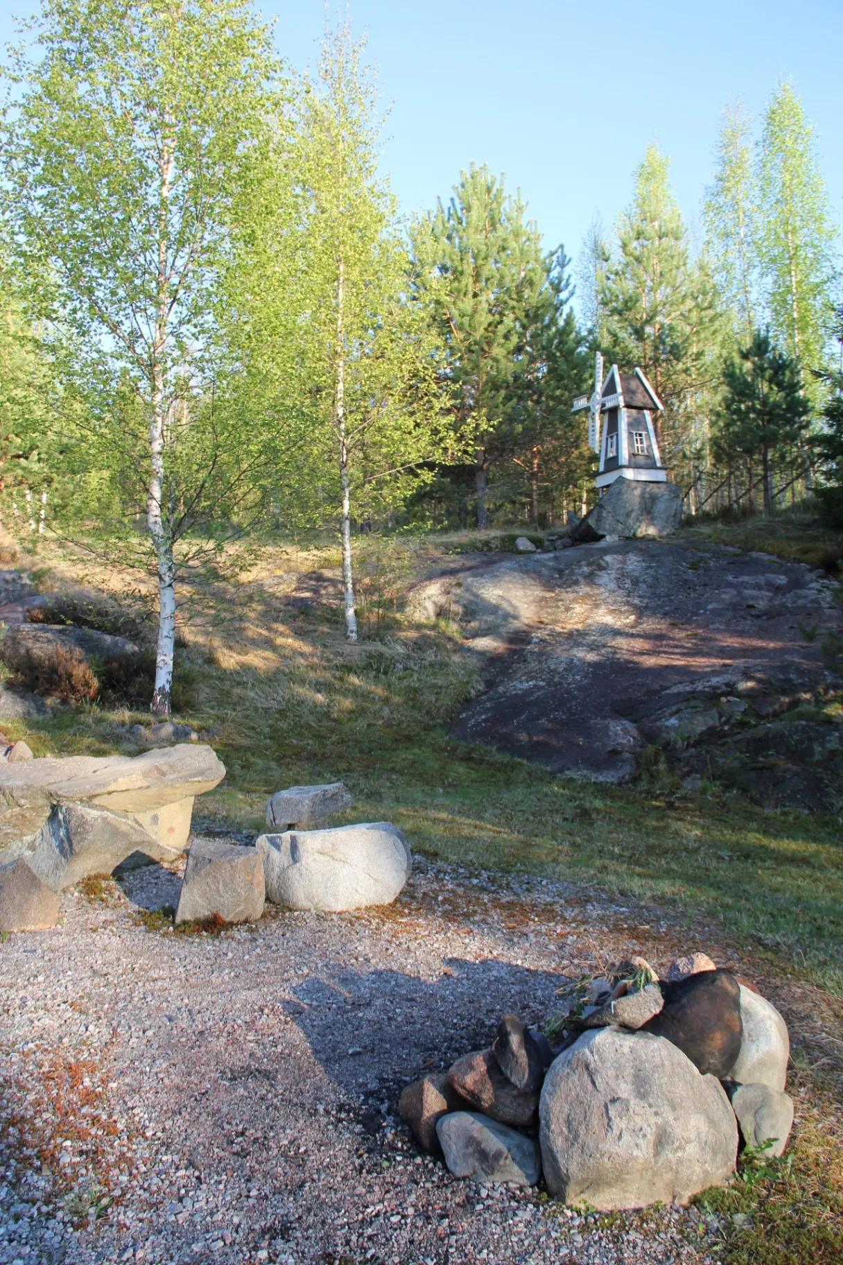 Decorative windmill on a rocky outcrop with a fire pit below